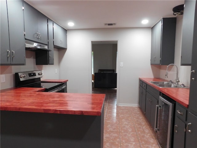 kitchen with butcher block countertops, stainless steel electric range, sink, and beverage cooler