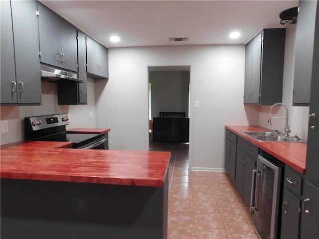 1408 Rose Dr, Alice, TX 78332 - kitchen featuring stainless steel electric range, a sink, under cabinet range hood, butcher block counters, and beverage cooler