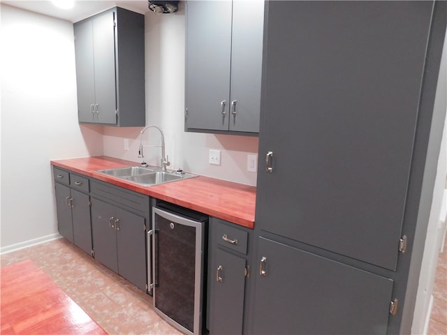 kitchen featuring gray cabinetry, beverage cooler, sink, and light tile patterned floors