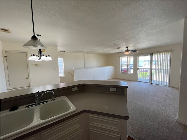 kitchen with carpet flooring, hanging light fixtures, a textured ceiling, and sink