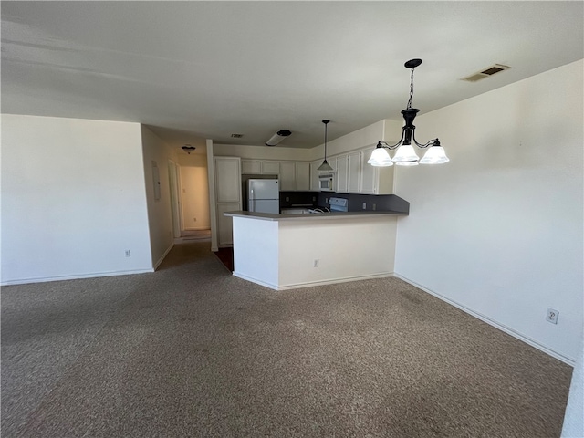 kitchen featuring dark colored carpet, white cabinets, kitchen peninsula, white appliances, and decorative light fixtures