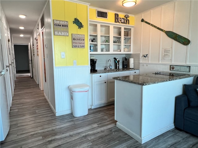 kitchen featuring crown molding, dark stone counters, white cabinetry, sink, and hardwood / wood-style floors