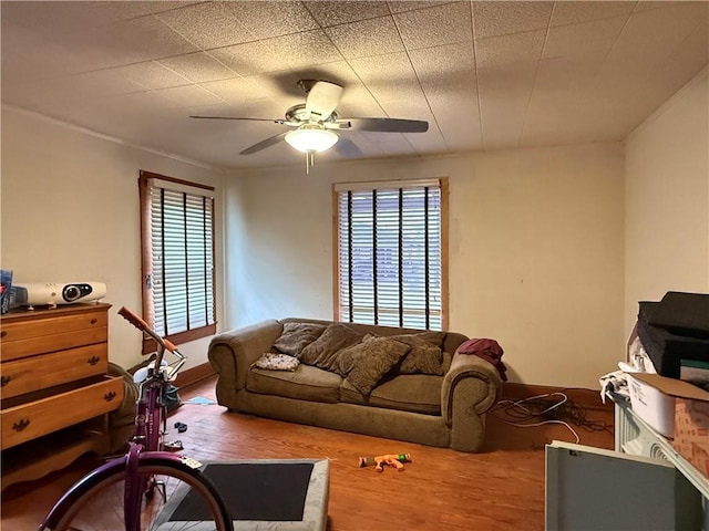 living area featuring a wealth of natural light, wood finished floors, and a ceiling fan