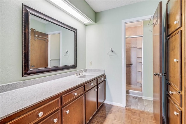 bathroom featuring vanity, parquet floors, and a shower with shower door