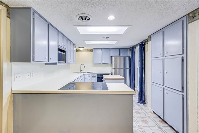 kitchen featuring kitchen peninsula, sink, a textured ceiling, and black appliances