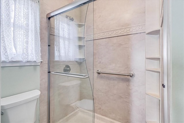 bathroom with toilet and a shower with shower door