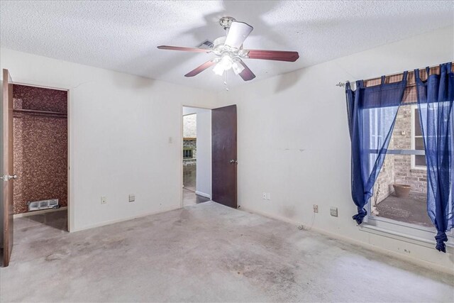 unfurnished bedroom featuring ceiling fan, light carpet, and a textured ceiling