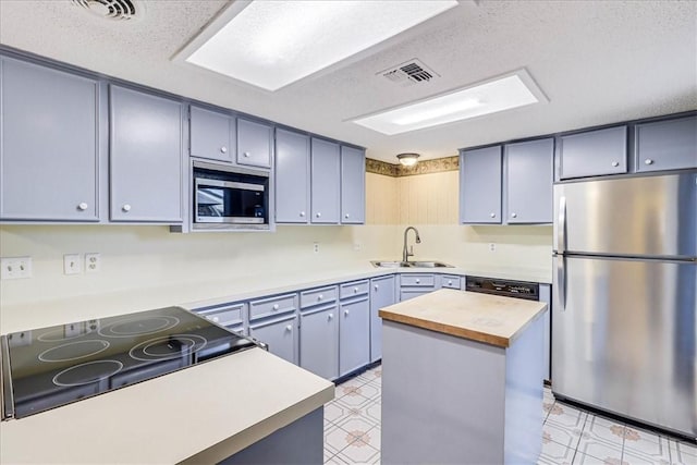 kitchen with a kitchen island, wood counters, sink, stainless steel appliances, and a textured ceiling