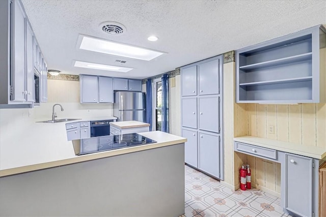 kitchen featuring sink, a textured ceiling, gray cabinets, kitchen peninsula, and black appliances