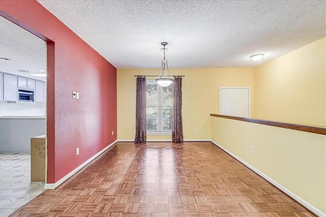 unfurnished dining area featuring light parquet flooring and a textured ceiling