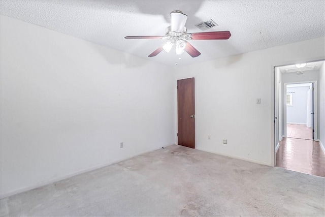 unfurnished room featuring ceiling fan, light colored carpet, and a textured ceiling