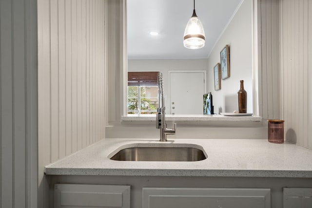 kitchen with sink, decorative light fixtures, and light stone counters