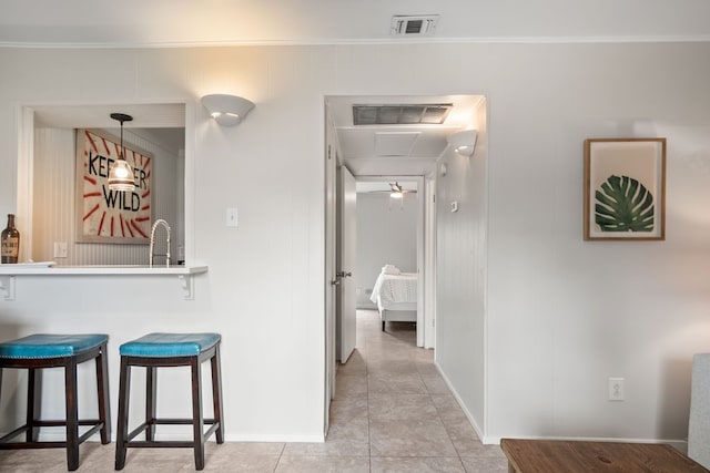 corridor with light tile patterned flooring, sink, and crown molding