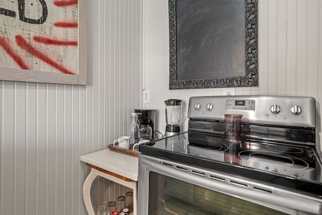 kitchen with stainless steel electric range and wooden walls