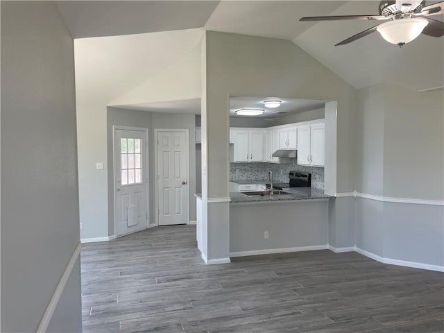 kitchen with lofted ceiling, backsplash, white cabinets, electric stove, and light stone countertops