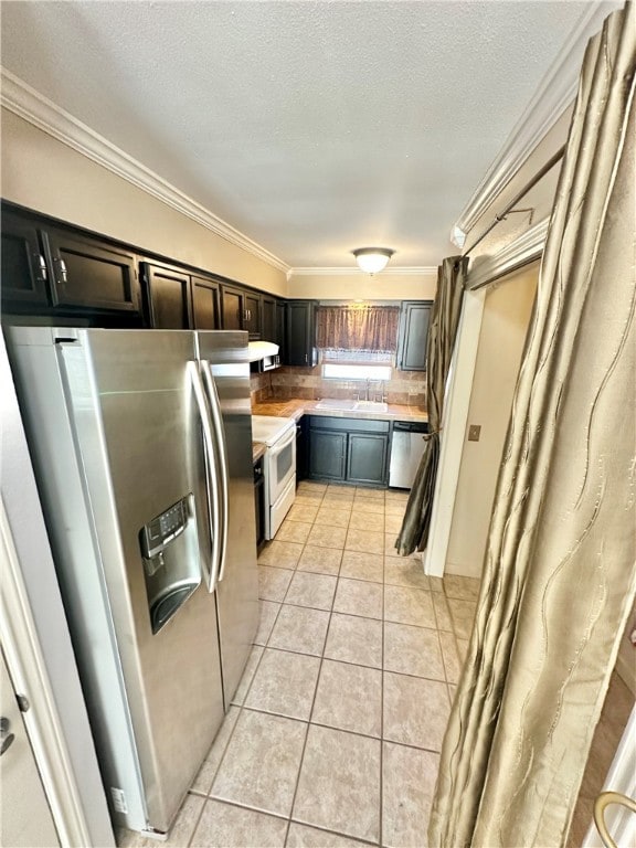 kitchen featuring light tile patterned flooring, crown molding, extractor fan, appliances with stainless steel finishes, and a textured ceiling