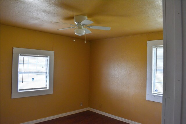 empty room featuring dark wood-type flooring and ceiling fan