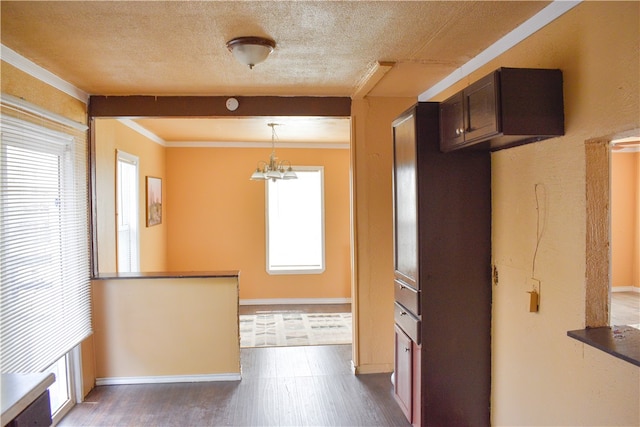 kitchen with ornamental molding, decorative light fixtures, a notable chandelier, a textured ceiling, and dark wood-type flooring