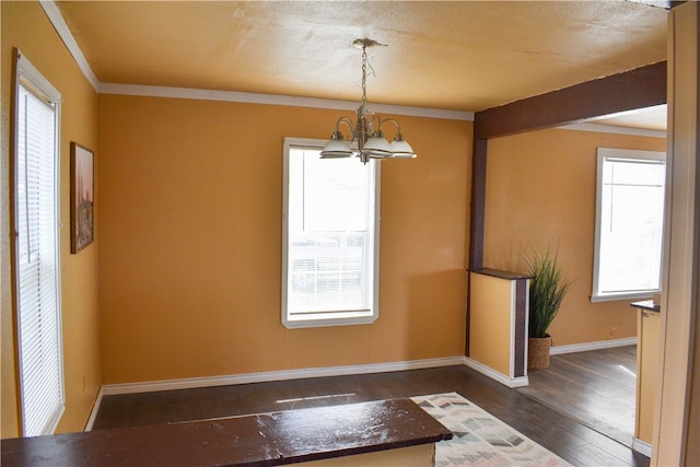 unfurnished dining area featuring dark hardwood / wood-style flooring, a notable chandelier, a textured ceiling, and crown molding