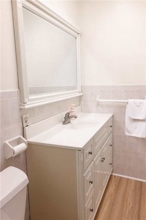 bathroom featuring hardwood / wood-style floors, vanity, tile walls, and toilet