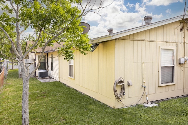 view of side of property featuring a yard and central AC