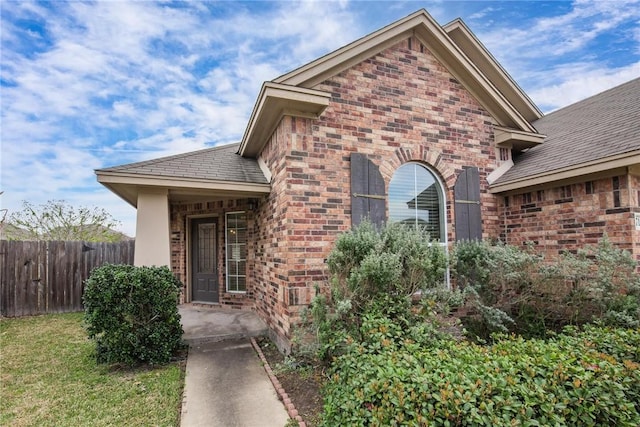 doorway to property with brick siding and fence