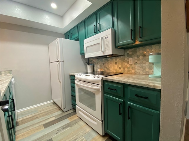 kitchen featuring backsplash, white appliances, green cabinets, and light hardwood / wood-style flooring