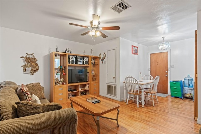 living room featuring ceiling fan with notable chandelier and light hardwood / wood-style floors