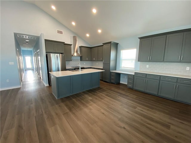 kitchen with decorative backsplash, stainless steel fridge, wall chimney exhaust hood, sink, and dark hardwood / wood-style floors