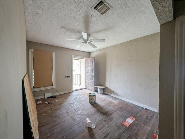 interior space featuring ceiling fan, visible vents, a textured ceiling, and a textured wall