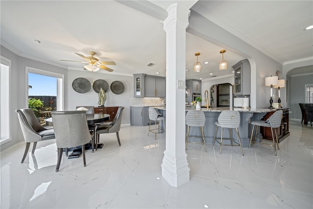 dining room featuring ornate columns, ceiling fan, and ornamental molding