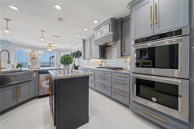 kitchen with gray cabinetry, a kitchen island, appliances with stainless steel finishes, pendant lighting, and sink