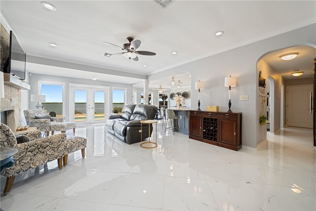 living room featuring ceiling fan, french doors, ornamental molding, and a fireplace