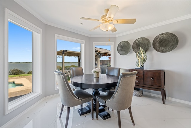 dining room featuring ceiling fan, a water view, and ornamental molding