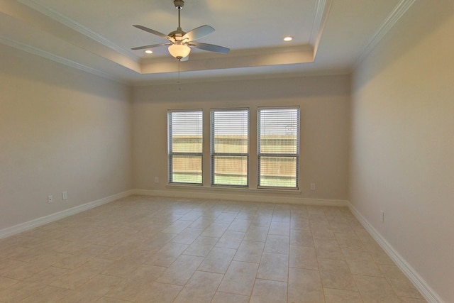 tiled empty room with ceiling fan, a raised ceiling, and ornamental molding