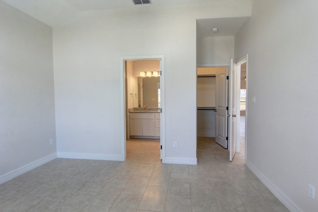 unfurnished bedroom featuring ensuite bathroom and a spacious closet