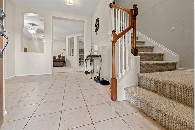 foyer entrance with stairs, ceiling fan, baseboards, and light tile patterned floors