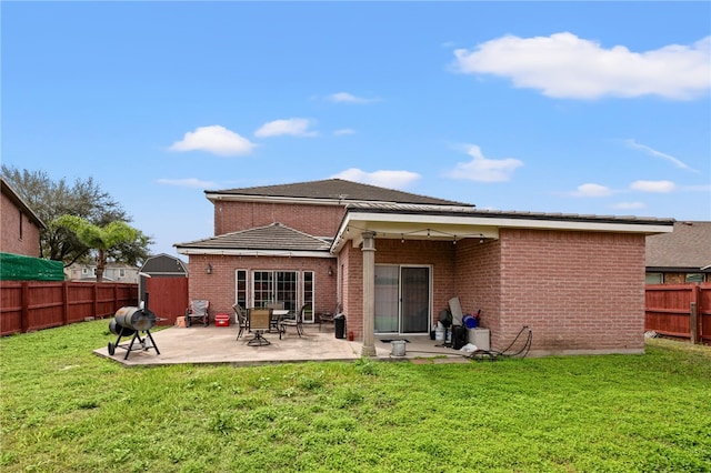 rear view of house with a patio, a yard, a fenced backyard, and brick siding