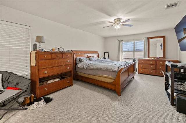 bedroom featuring a ceiling fan, visible vents, and light carpet