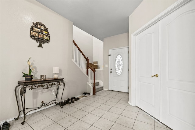 entryway featuring light tile patterned floors, stairway, and baseboards