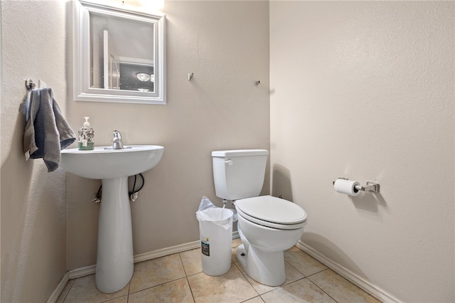 half bathroom featuring baseboards, toilet, and tile patterned floors