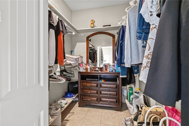 spacious closet featuring arched walkways and light tile patterned flooring