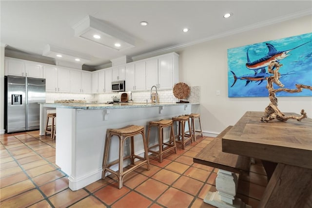 kitchen with a peninsula, appliances with stainless steel finishes, white cabinets, and crown molding