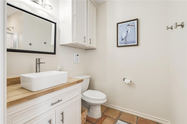 bathroom with baseboards, vanity, toilet, and tile patterned floors