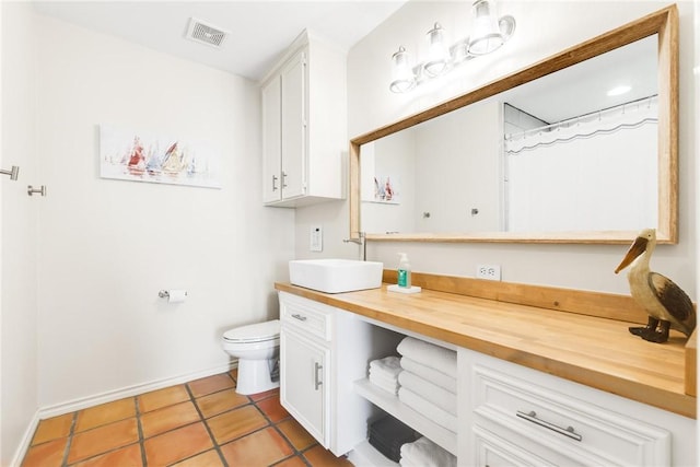 bathroom with toilet, vanity, baseboards, visible vents, and tile patterned floors