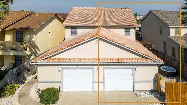 view of front of home featuring a garage, concrete driveway, a tile roof, fence, and stucco siding