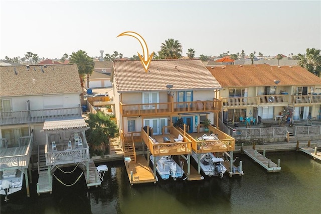 rear view of house with a residential view, a tile roof, a water view, and a balcony