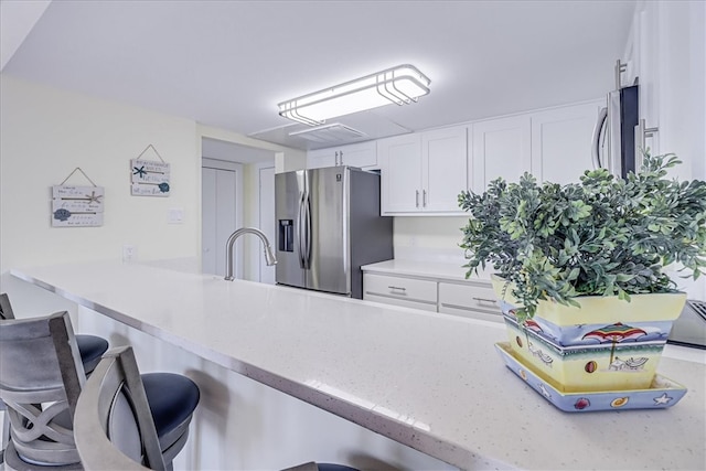 kitchen with sink, kitchen peninsula, stainless steel refrigerator with ice dispenser, a kitchen bar, and white cabinets