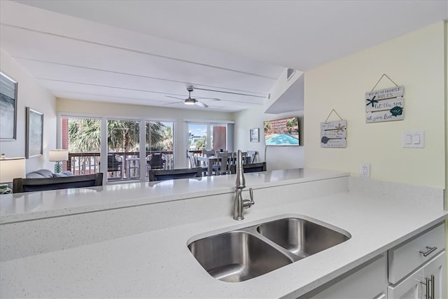 kitchen with sink, light stone counters, and ceiling fan