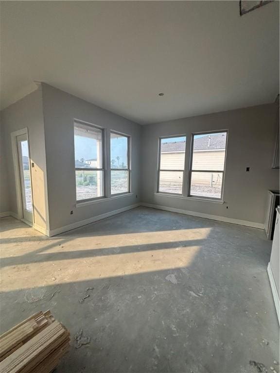 3102 Adak Ct, Corpus Christi, TX 78414 - unfurnished living room with unfinished concrete flooring, baseboards, and plenty of natural light